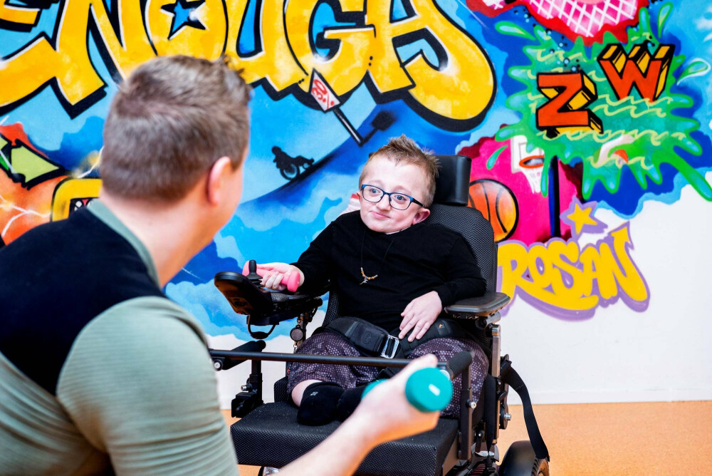 Jongen in rolstoel met behandelaar op Hengeveld