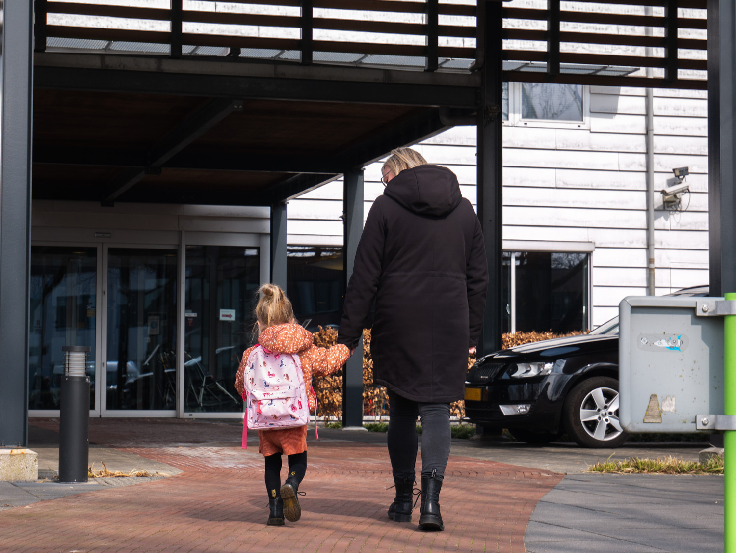 Rhodé loopt hand in hand met haar moeder Berdien naar de ingang van het gebouw Kinderrevalidatie van Vogellanden