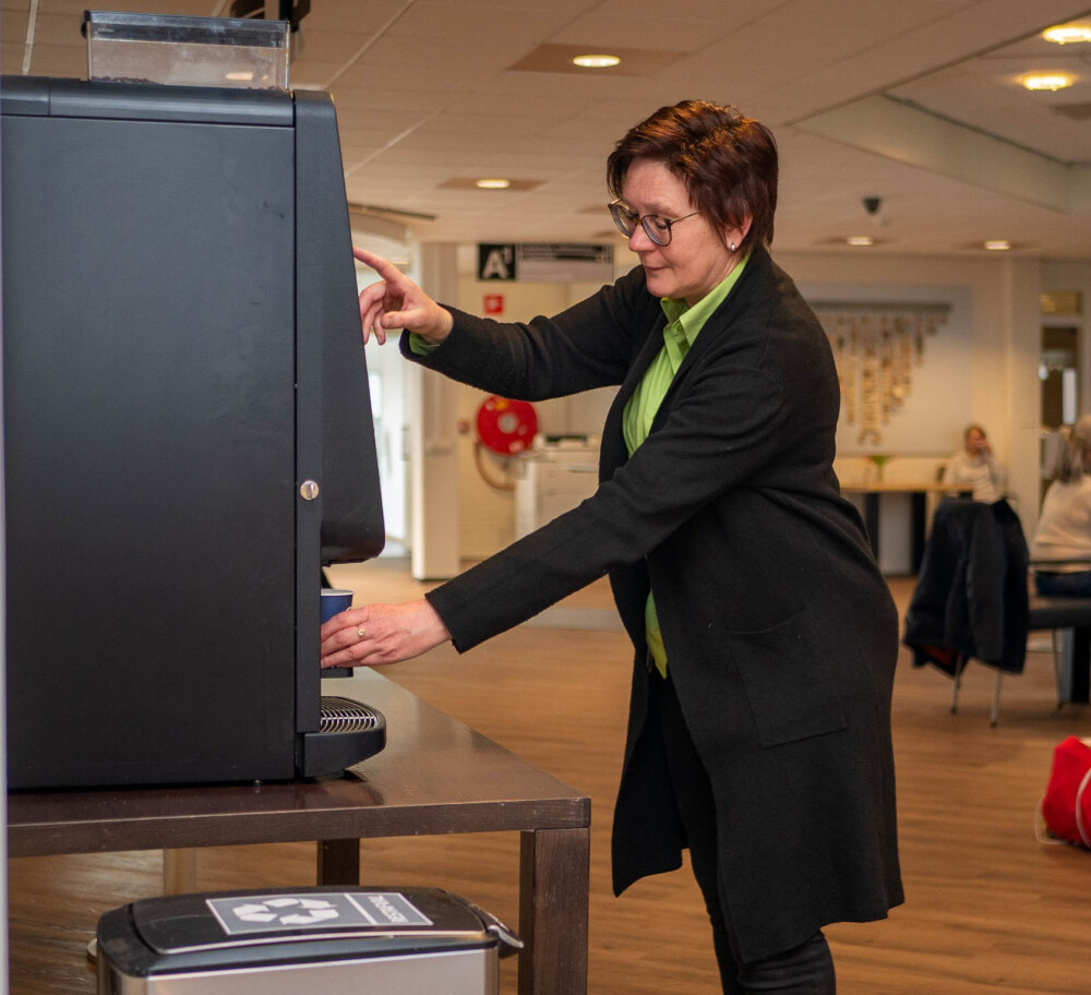 Marijke haalt een kopje koffie bij het koffiezetapparaat