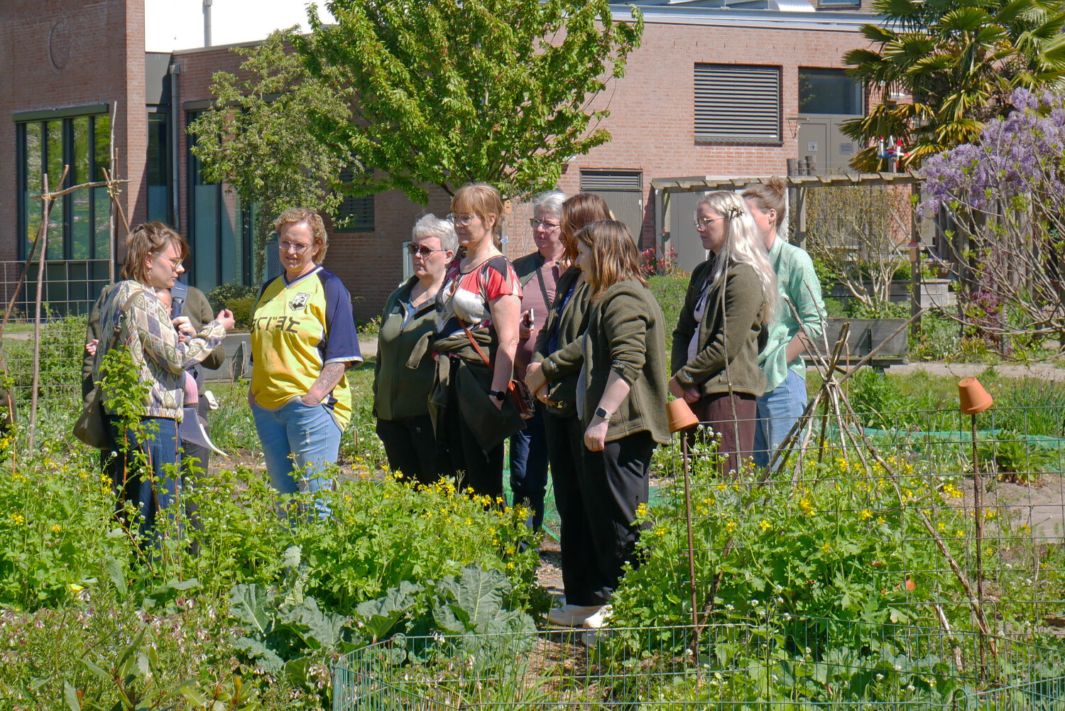 Het bezoek staat tussen de planten in de Beleeftuin