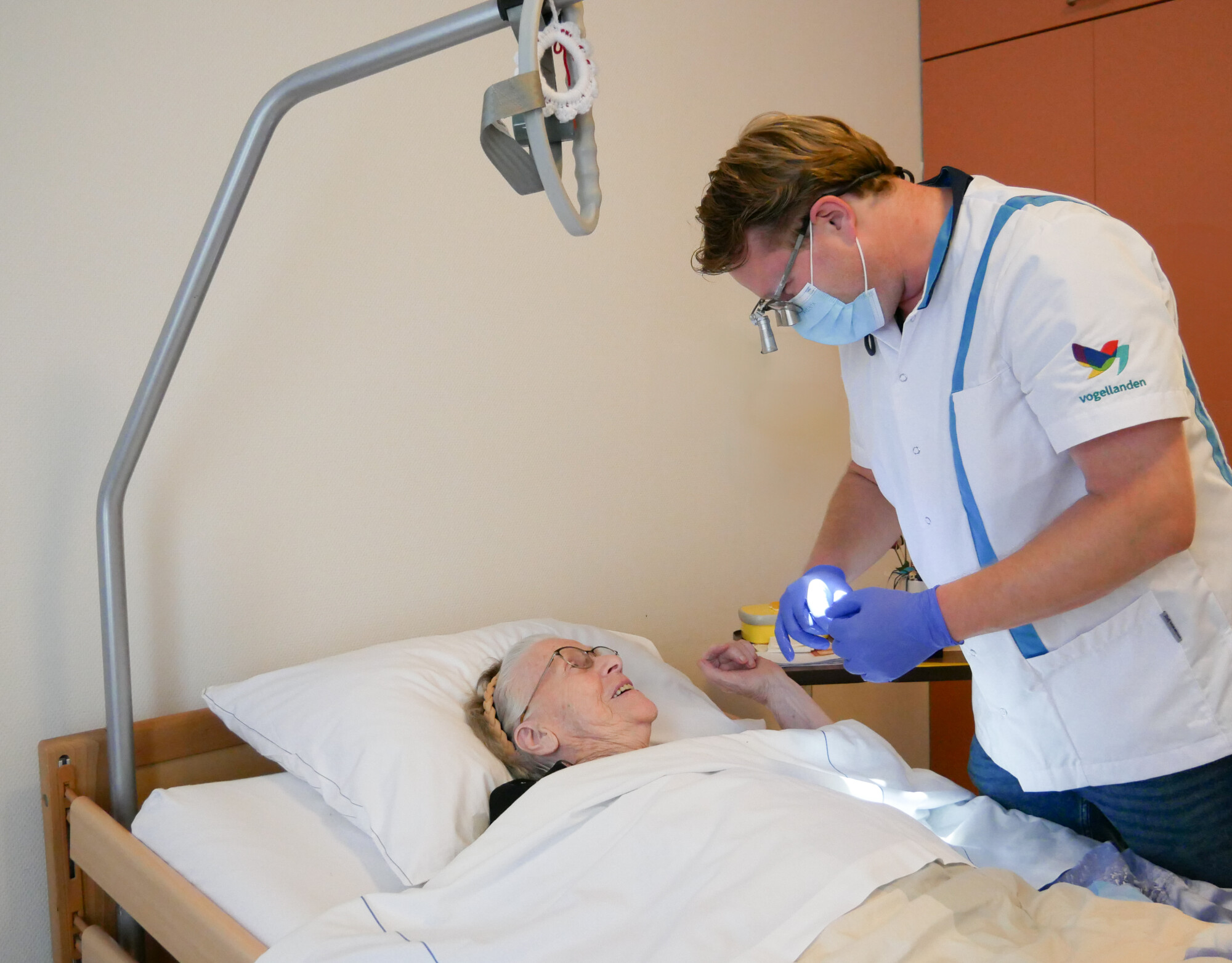 Tandarts helpt patiënt aan bed