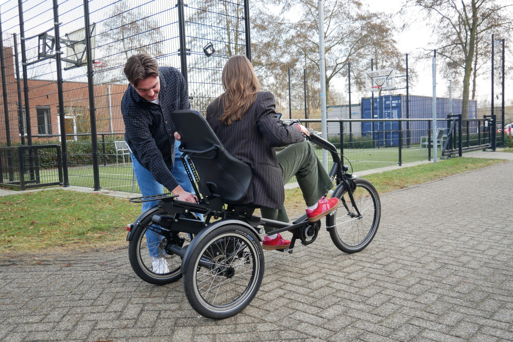 Jonas helpt een patiënt buiten met de driewielfiets