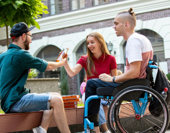 Drie jongvolwassenen zitten buiten gezellig bij elkaar