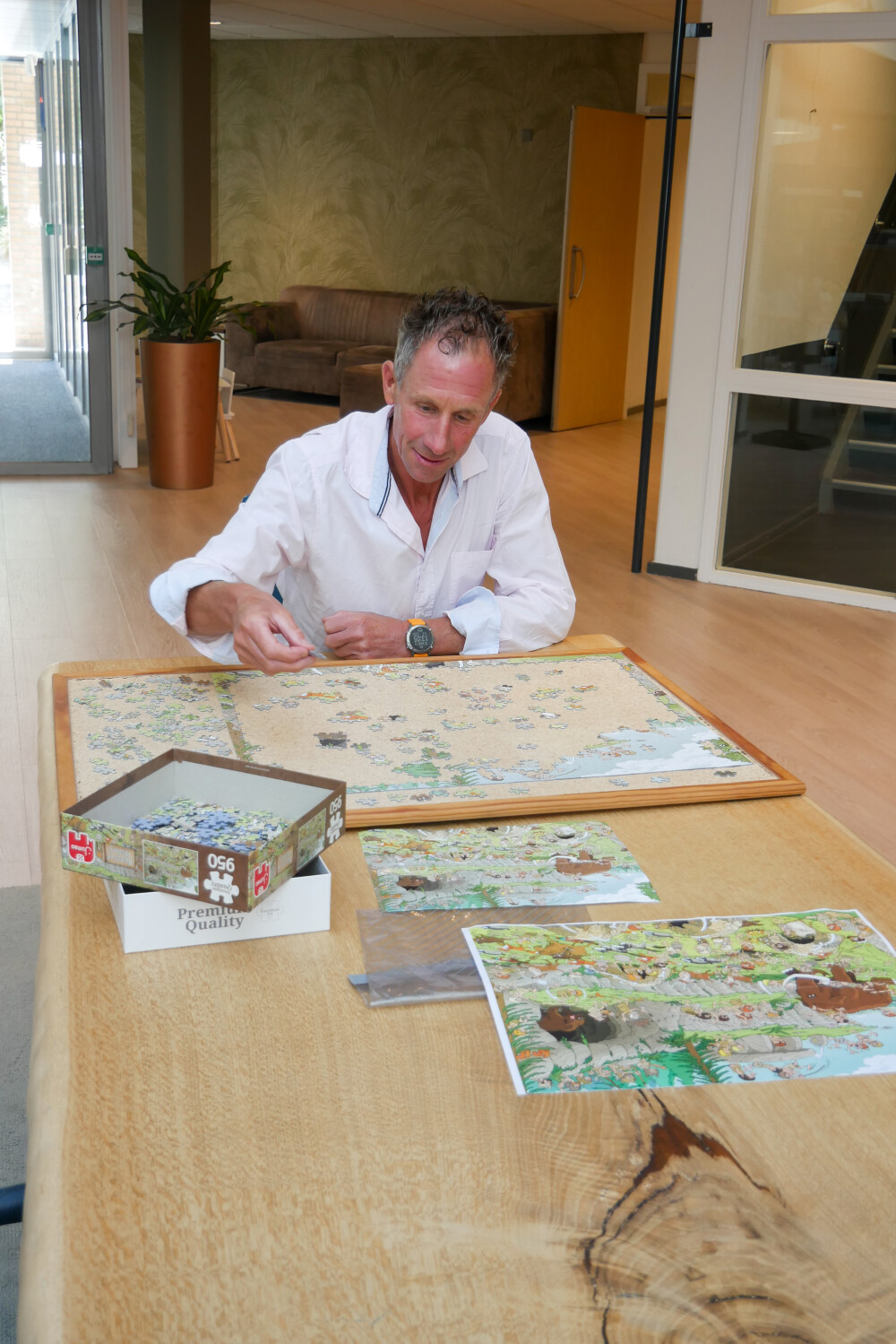 Johan maakt een puzzel aan tafel in de centrale hal van Vogellanden
