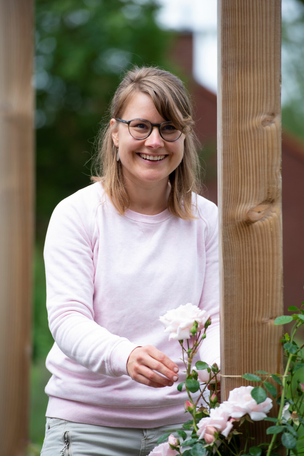 Milena staat bij roze roos in de tuin van Vogellanden
