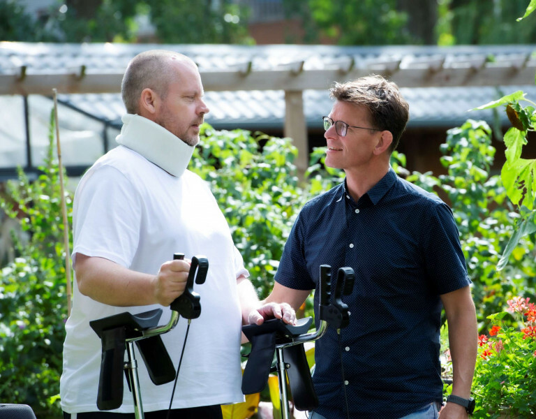 Patiënt en behandelaar in gesprek met elkaar in de tuin van Vogellanden