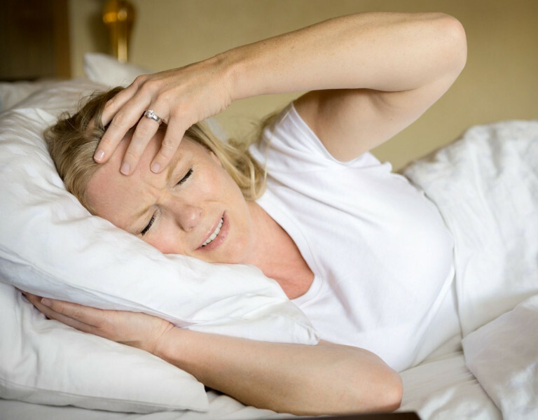 Vrouw met erge hoofdpijn in bed