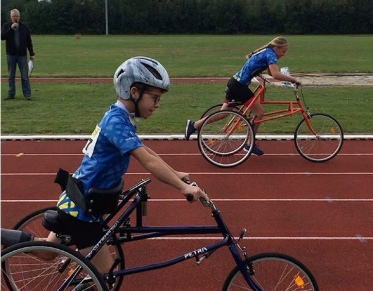 Twee jongeren met een beperking doen een aangepaste sport op de atletiekbaan