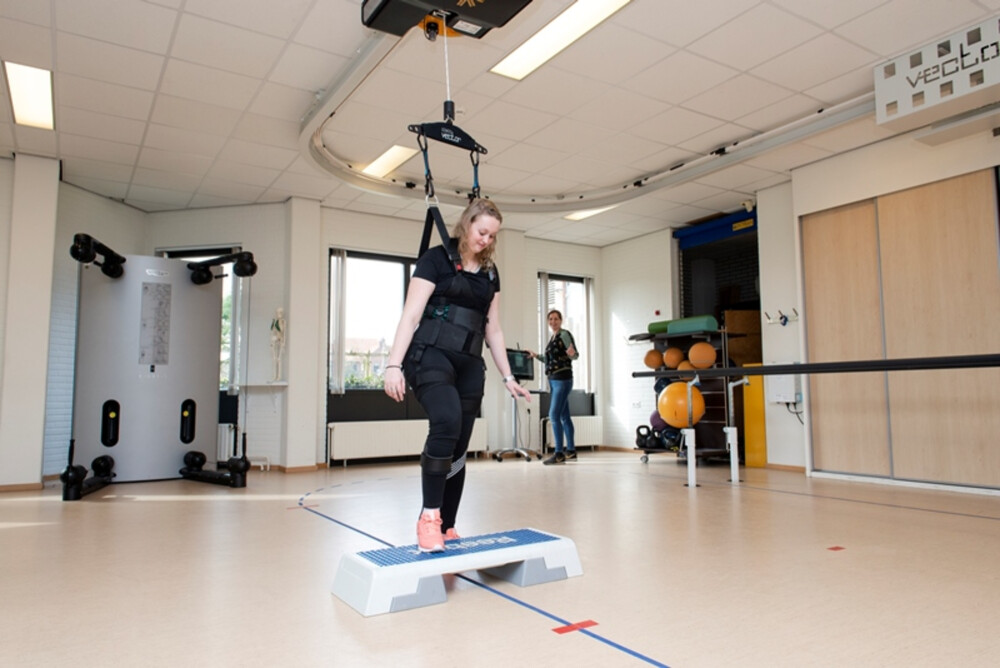 Romy loopt in het Body Weight Support syteem met een fysiotherapeut die haar begeleid