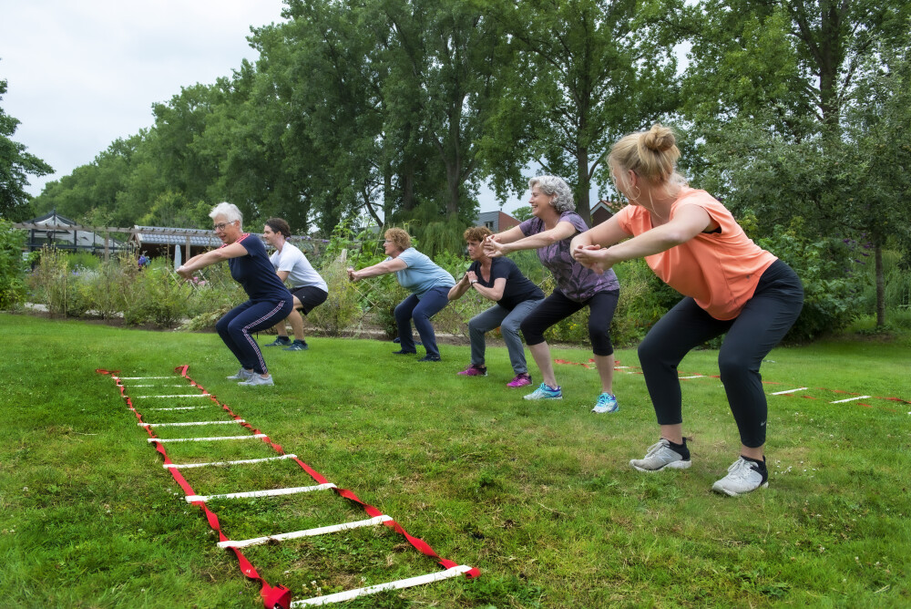 Tini sport met een groep in de tuin van Vogellanden