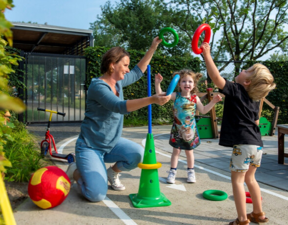 Leidster en kinderen spelen samen buiten met ringen