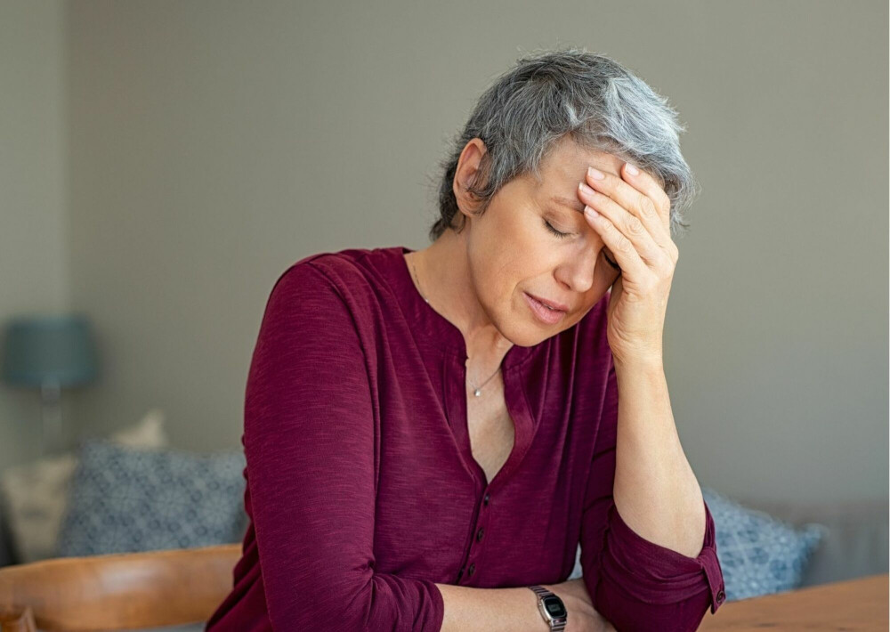 Vrouw aan tafel met hand aan haar hoofd